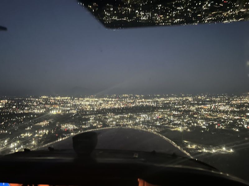 Night flight over Bakersfield city lights seen through the windshield of a small airplane